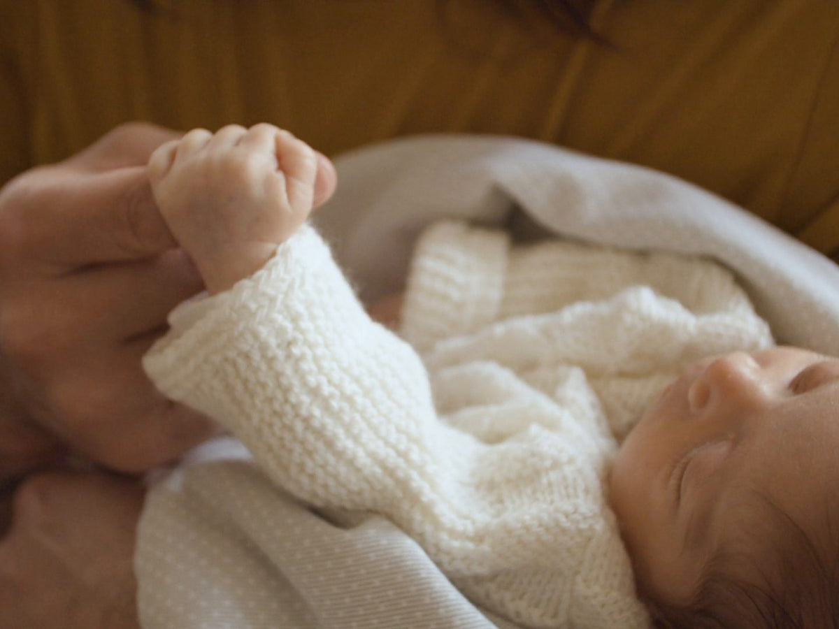 Nyfödd bebis håller ett finger