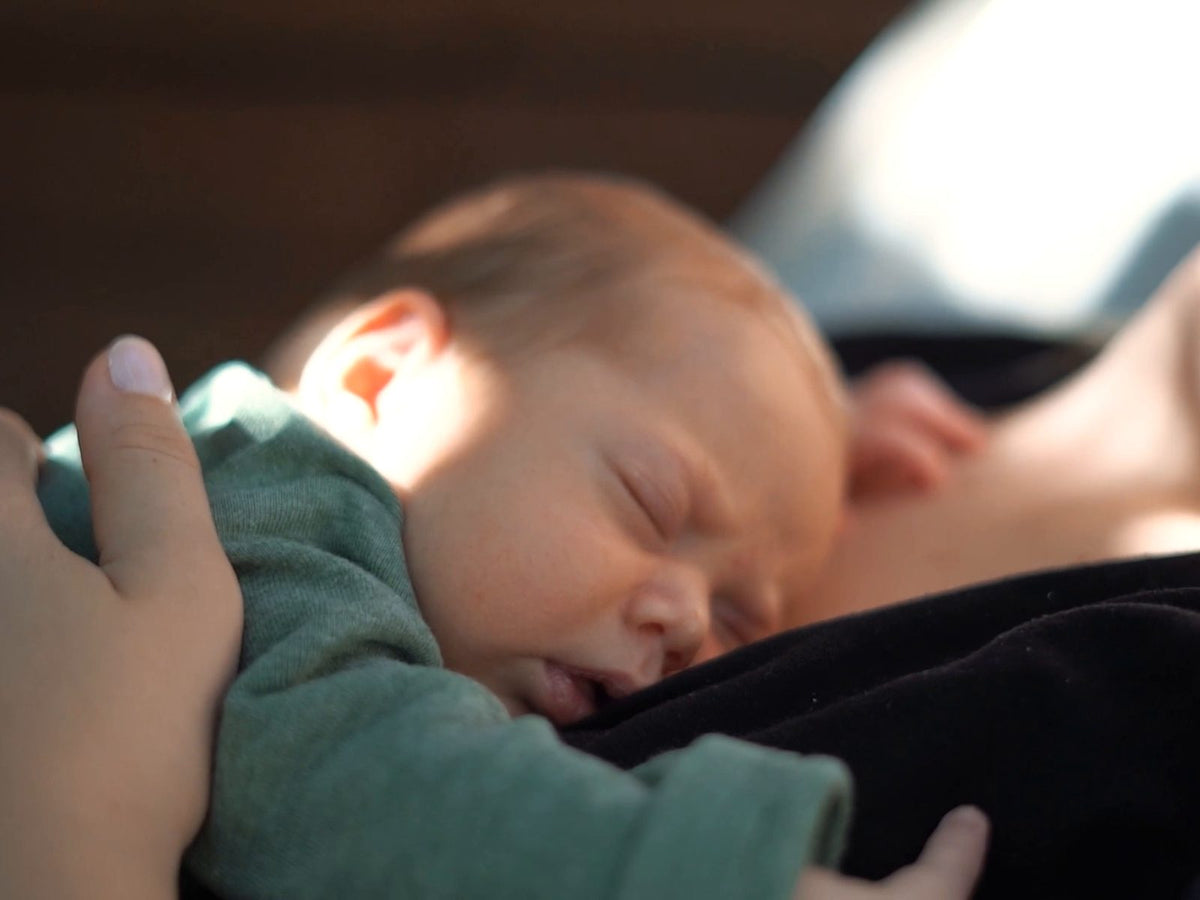 Bebis sover på mammas bröst