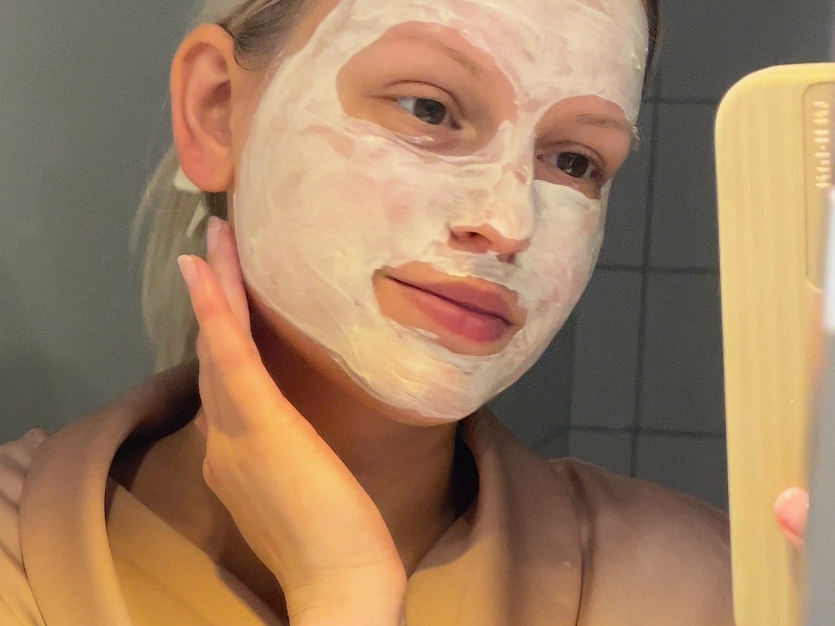 Kvinna med lermask framför spegeln