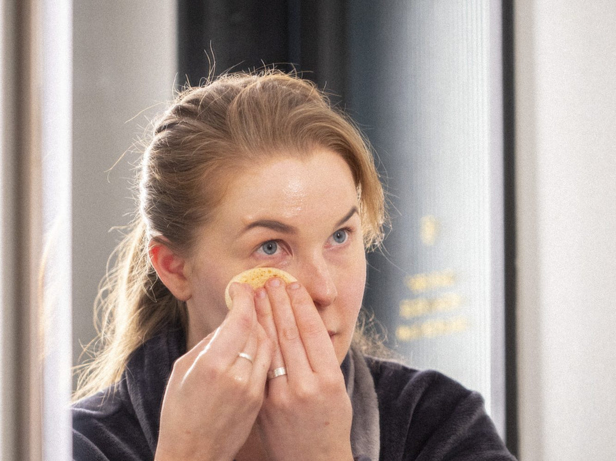 Kvinna rengör ansiktet framför spegeln