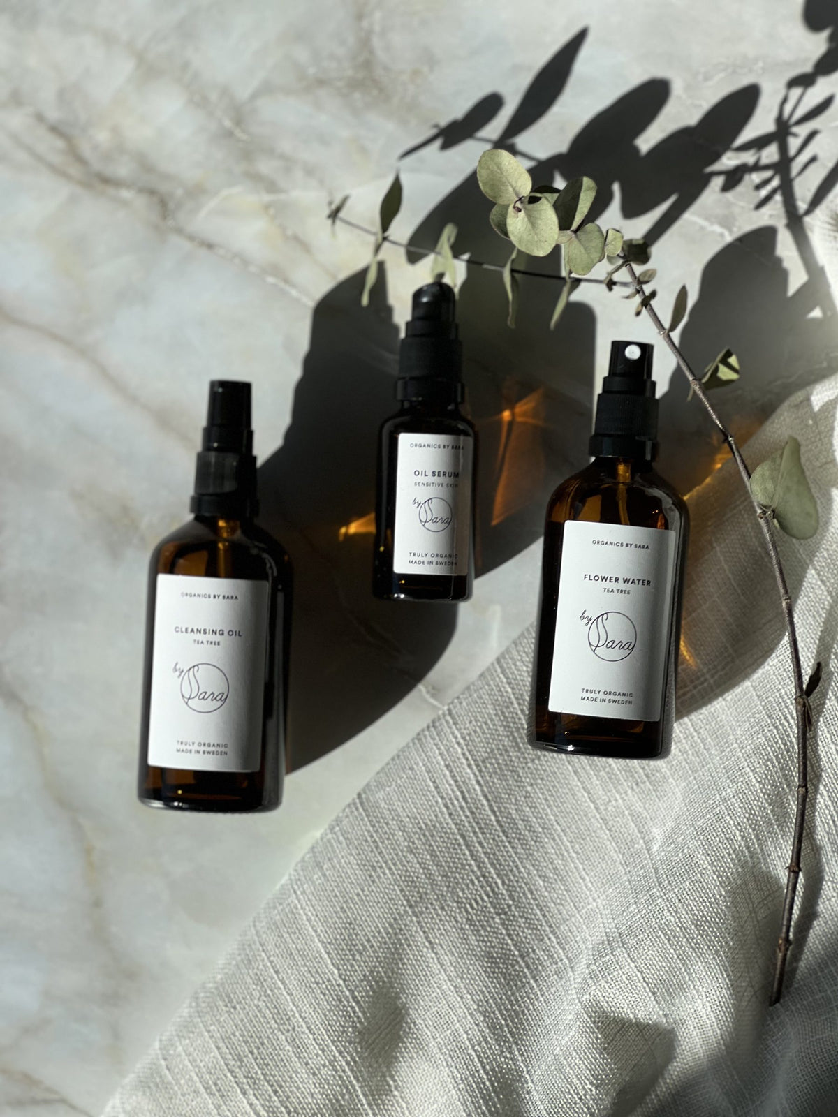 Ekologiskt serum och ansiktsvatten på marmor med eukalyptusskugga